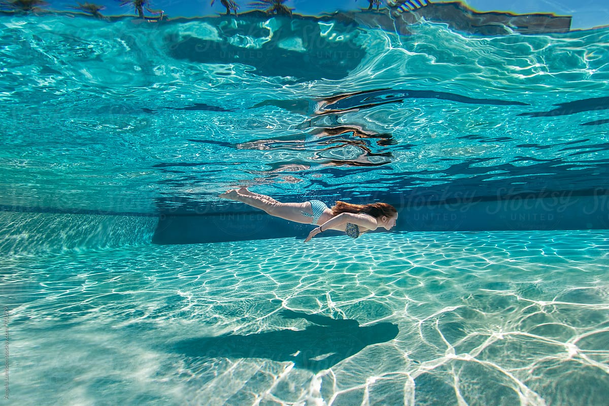 Girl swimming underwater in a large blue swimming pool