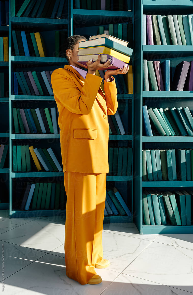 Anonymous person in suit holding stack of books in front of face