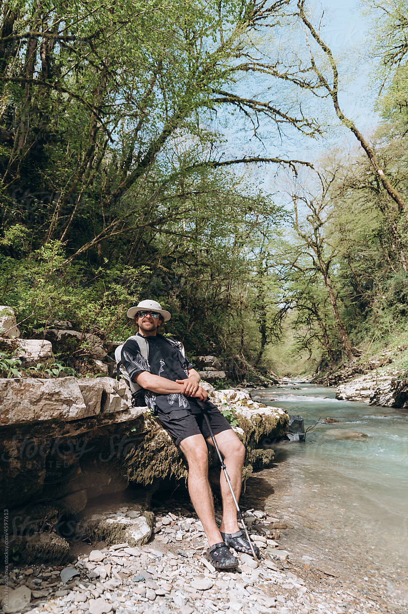 Traveling man resting near river during trekking