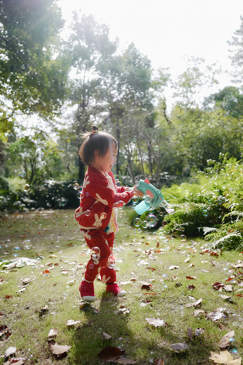 Asian baby chasing bubbles in the park