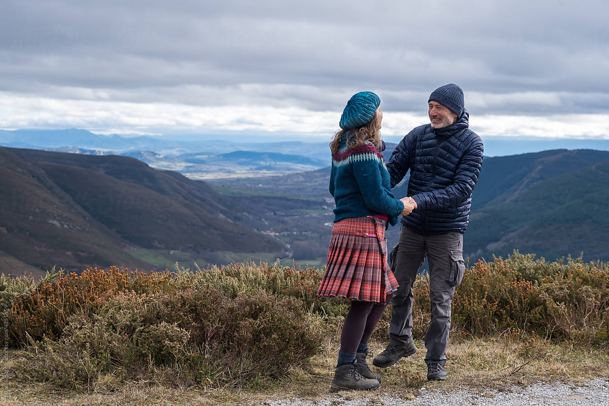 a couple holding hand on a mountaintop