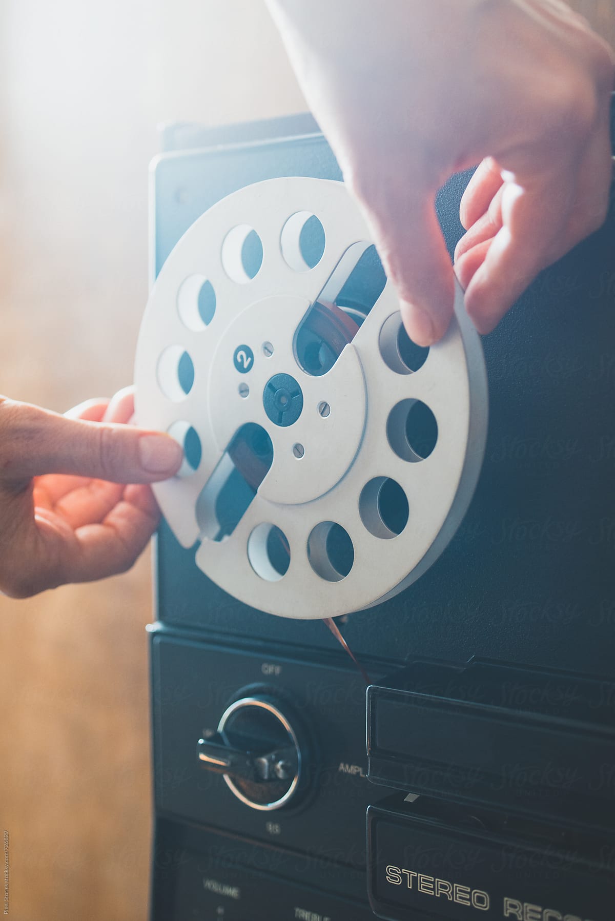 Person placing a reel on a reel-to-reel tape recorder