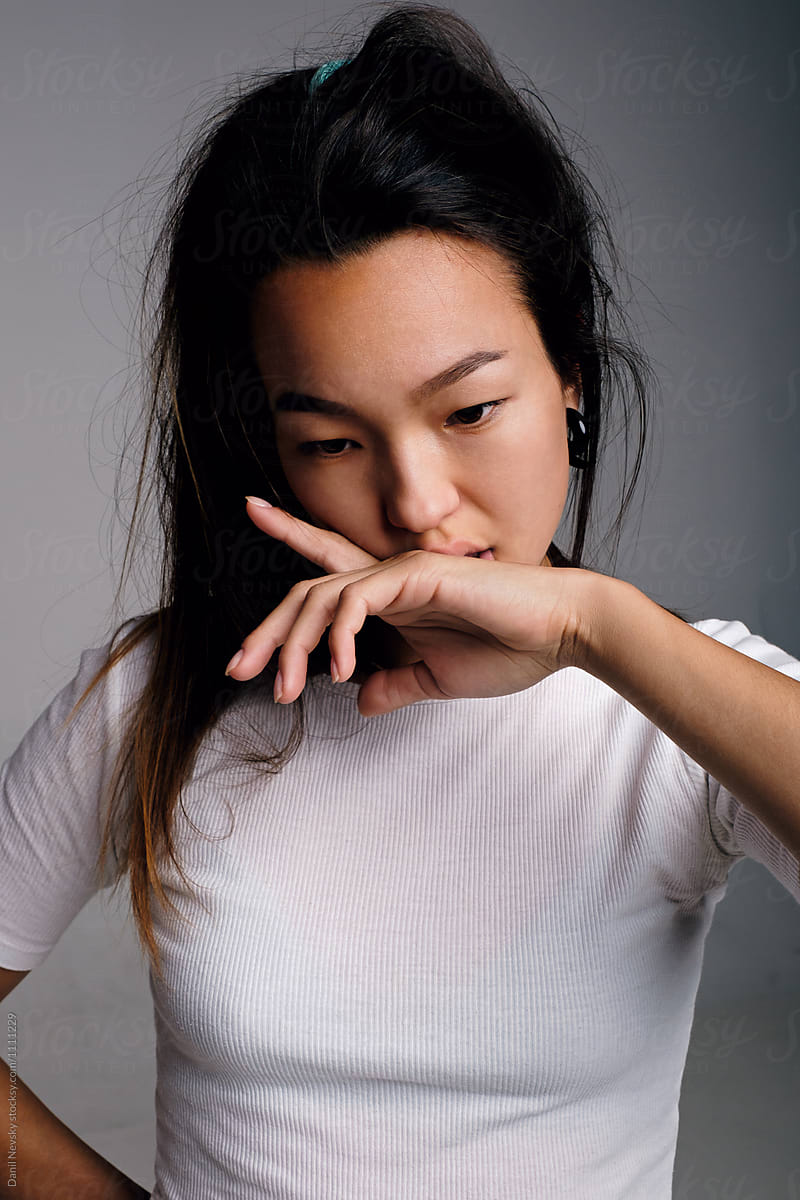 Asian black-haired woman with hand at lips looking down