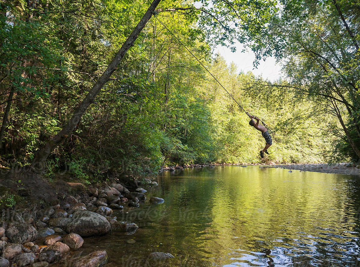 Boy On Rope Swing Over Creek by Stocksy Contributor Ronnie Comeau -  Stocksy