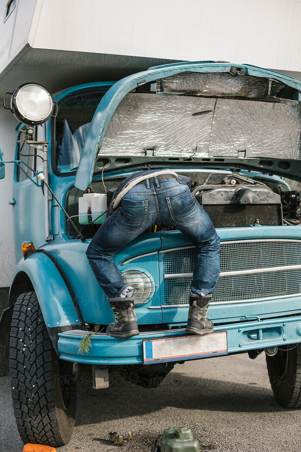 male mechanic repairing old truck in a funny way and showing his butt
