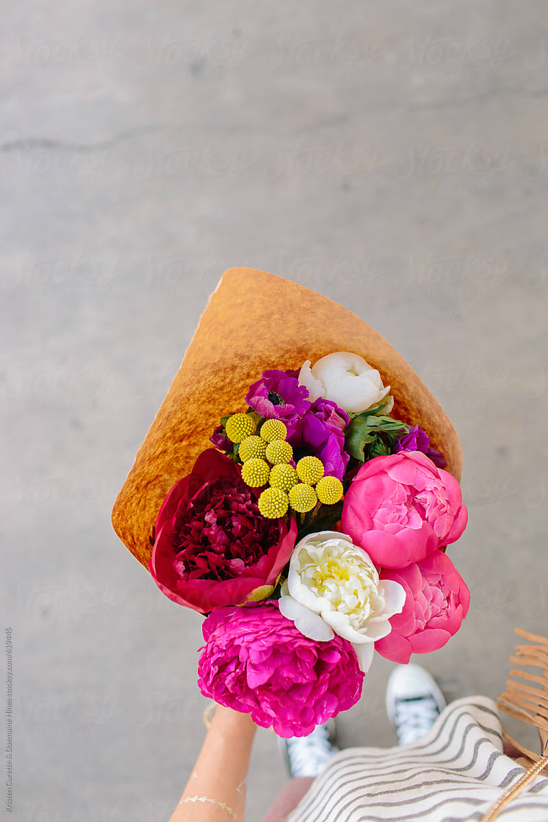 A first person view of someone holding a peony arrangement