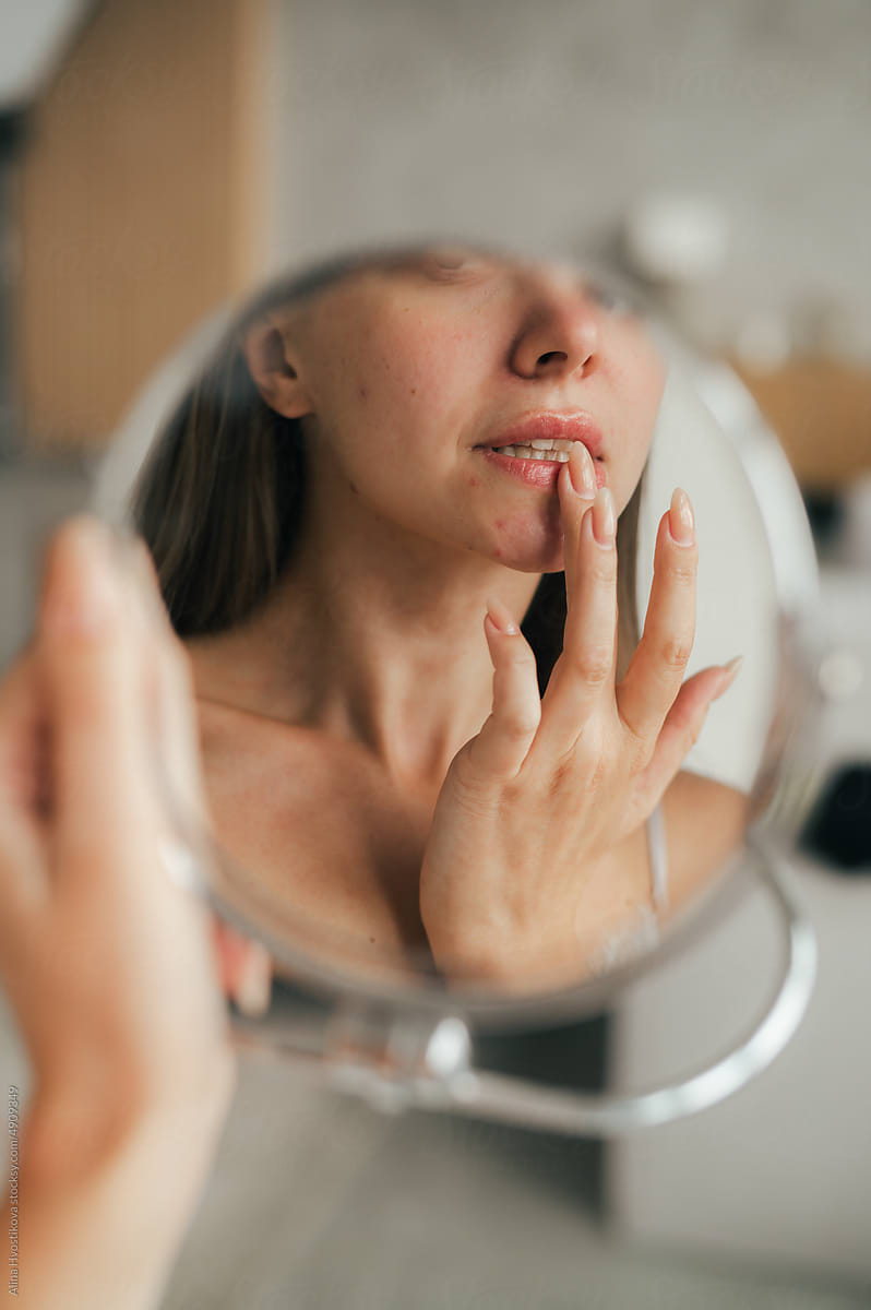 Anonymous woman applying cream on lips