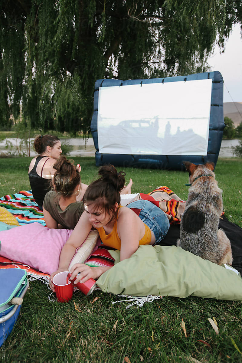 friends and family enjoy watching outdoor movie in yard