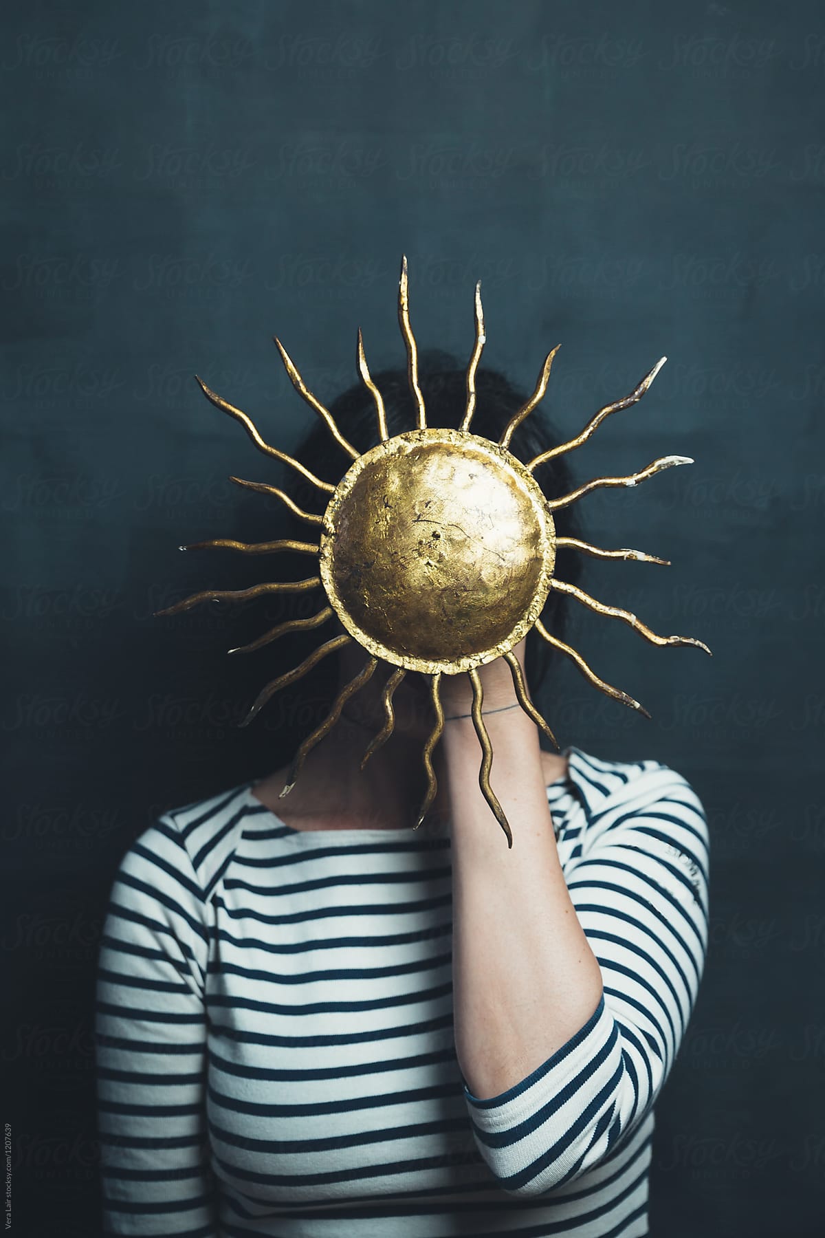 Woman hiding behind a golden sun