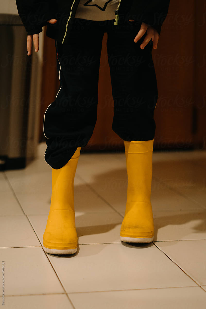 Little kid with yellow water boots at home