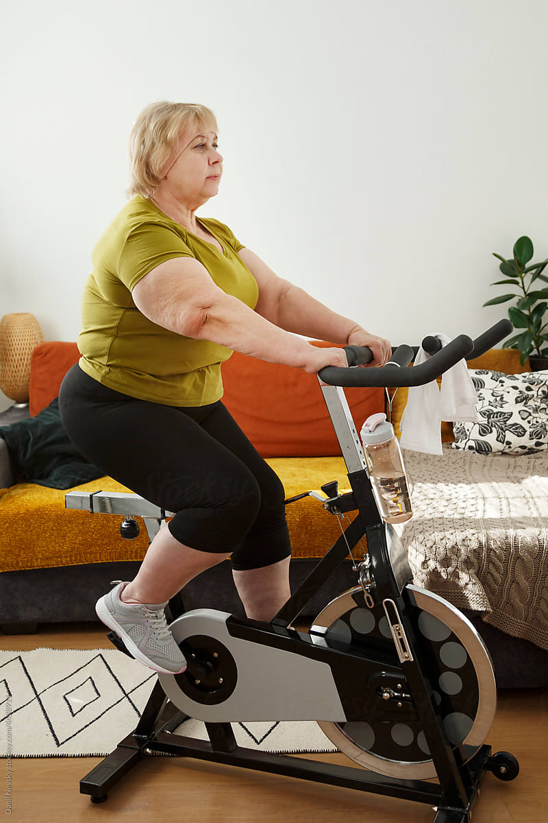 Plus size woman on exercise bike at home