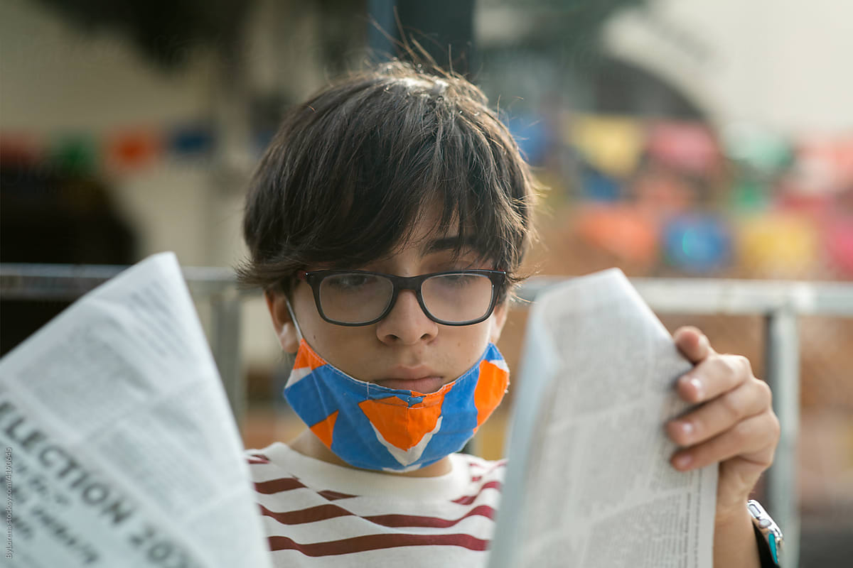 Teen boy reading newspaper