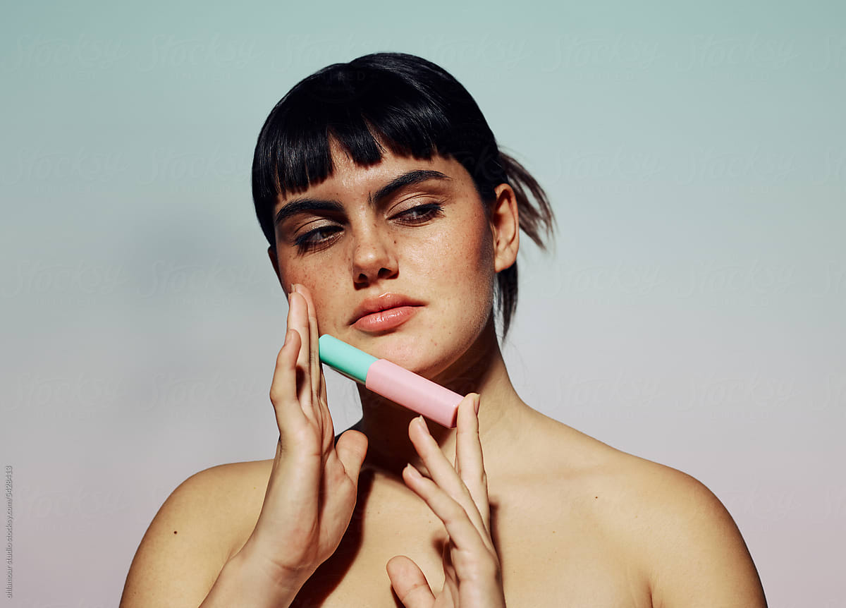 Woman with thick eyelashes holding mascara product