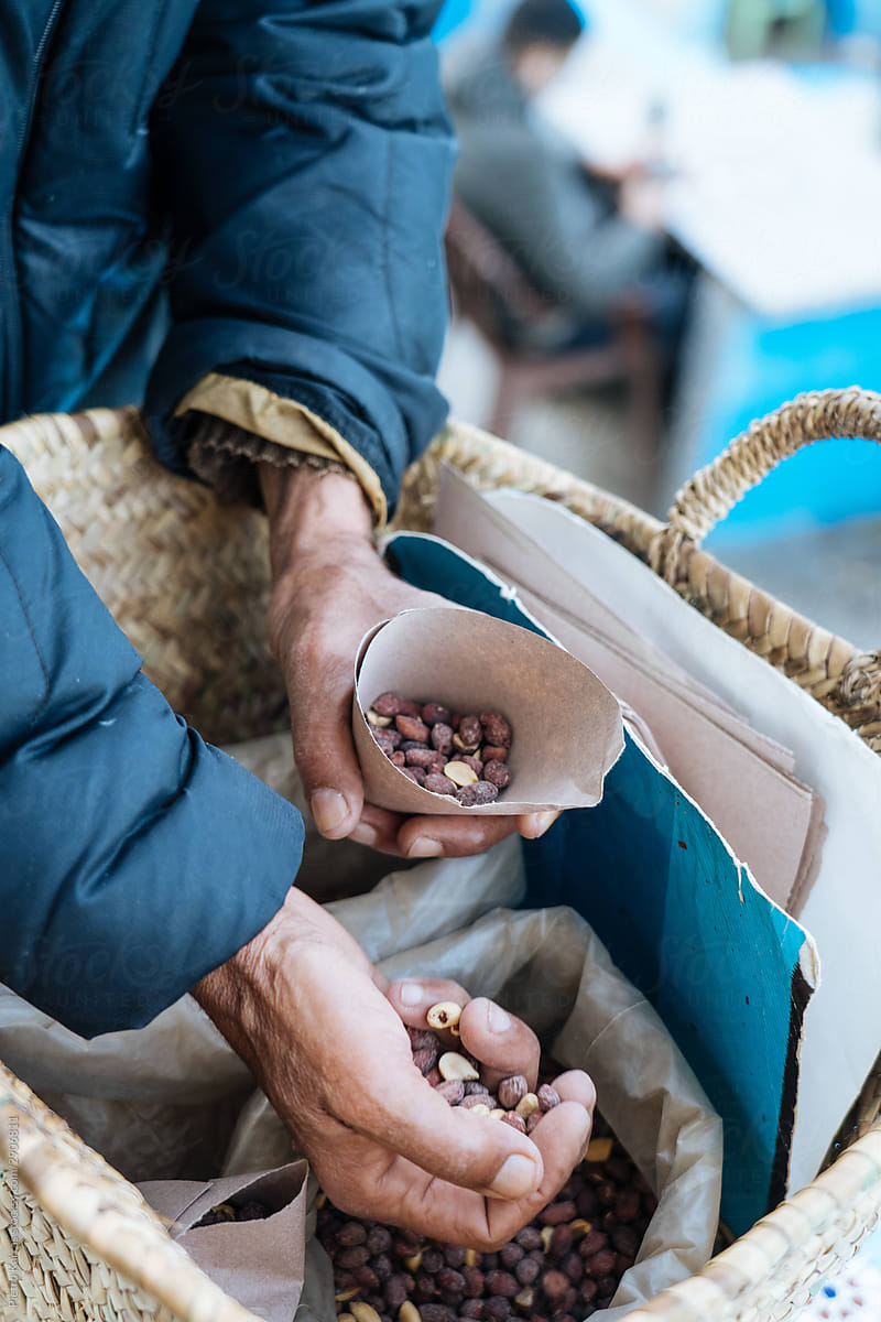 Elderly seller putting apricot bones in paper bag