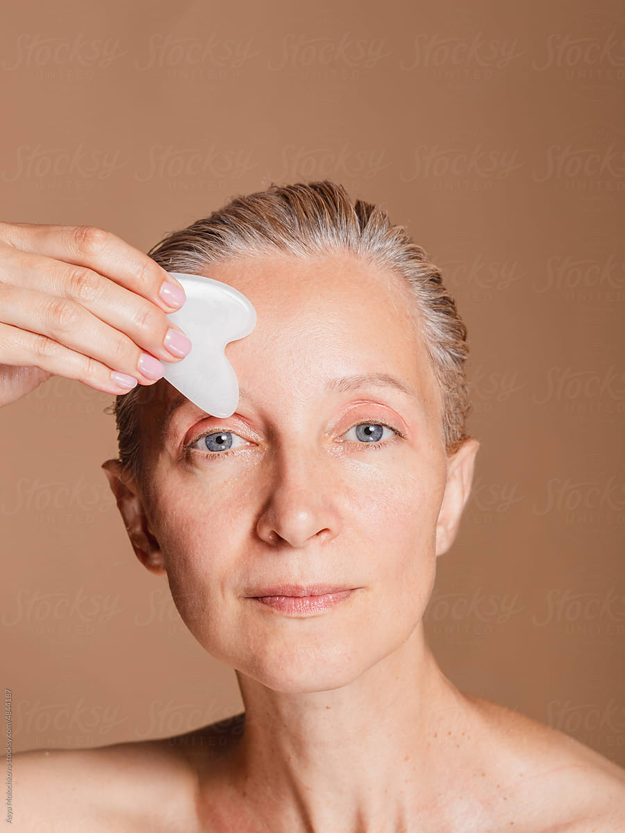 Middle aged woman using gua sha scraper