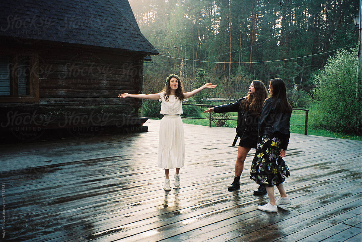 Three happy girl friends dancing in a forest on a wedding day