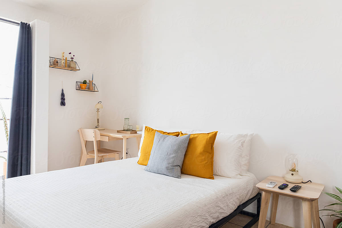 A bed with cushions and a white wall above for copyspace in a room