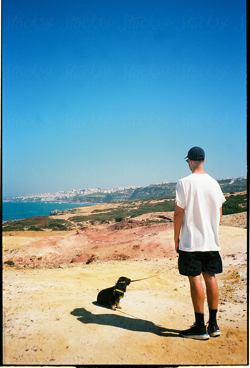 Analog portrait of a young man standing next to his dog