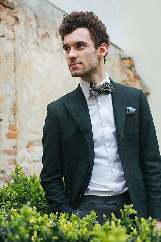 Outdoor Portrait of Young Stylish Caucasian Man in Green Jacket and Bow Tie