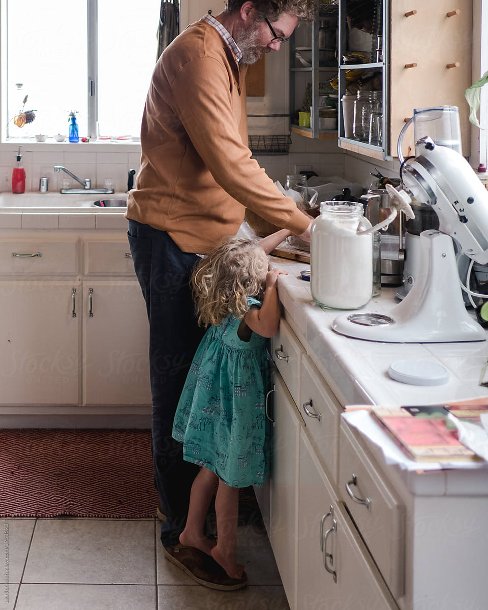 daddy and daughter baking in the kitchen , little girl standing on daddy\'s feet