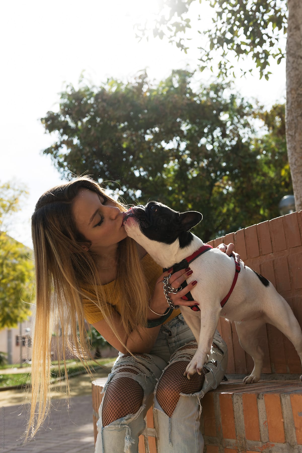 Trendy woman kissing with dog