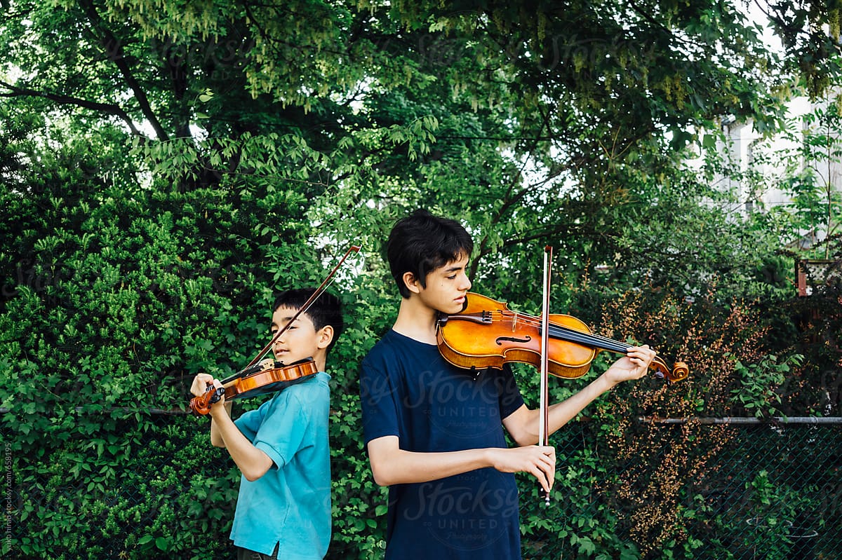 Asian brothers, practicing to play music instruments together at home