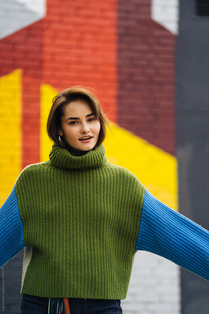 young woman in a sweater against the background of a painted wall
