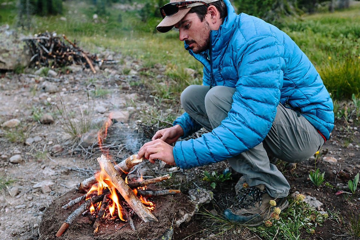 Man gathering wood and assembling small fire for camping