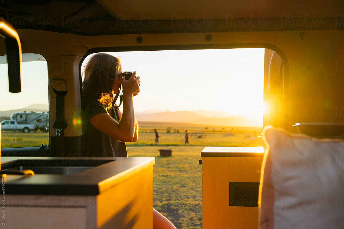 Photographer by her camper van taking a photo at sunset
