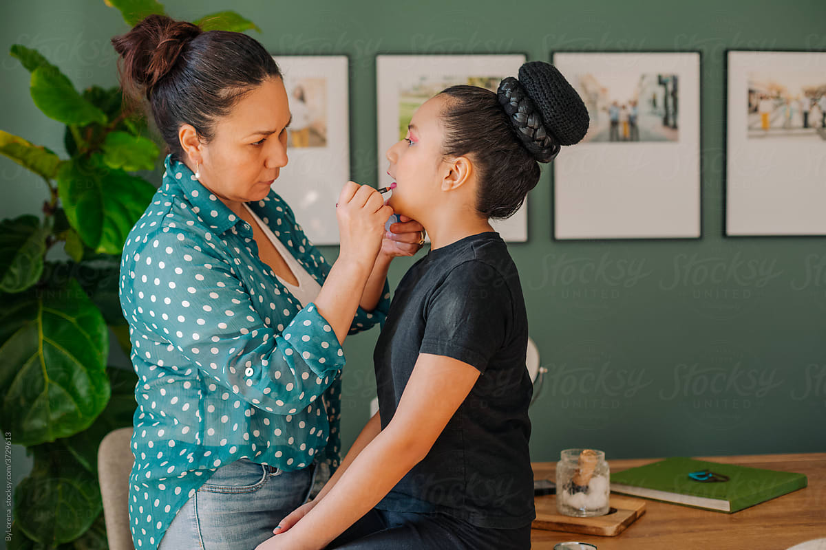 Mother applying makeup to her daughter for performance act
