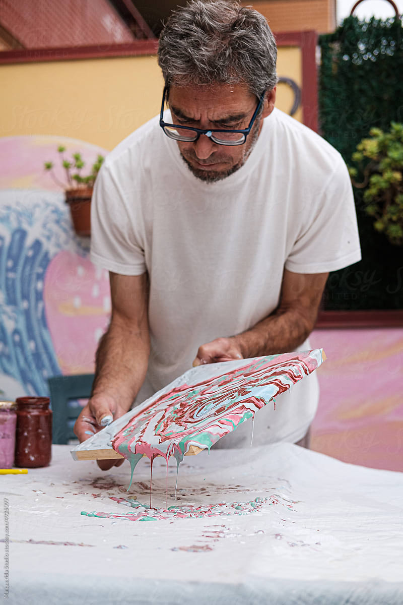 Middle aged artist pouring colorful paint