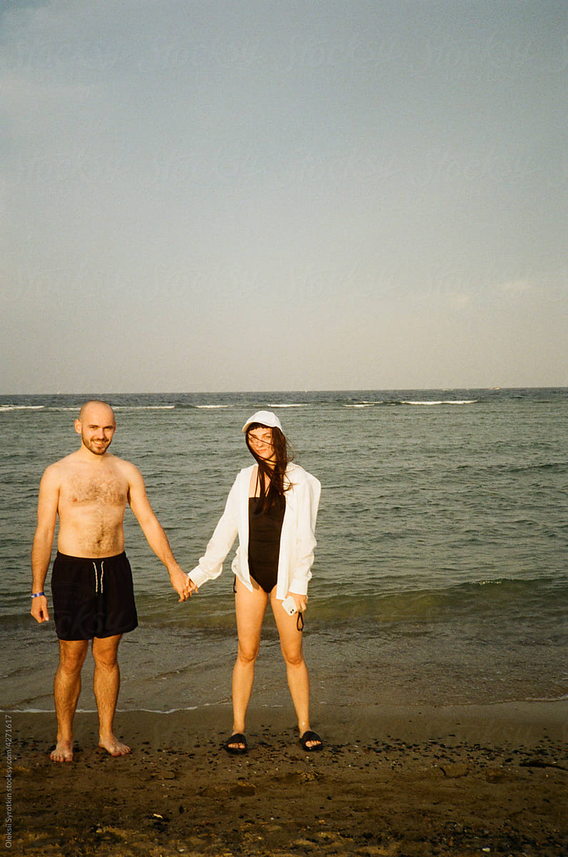 Couple holding by hands while posing on sea background