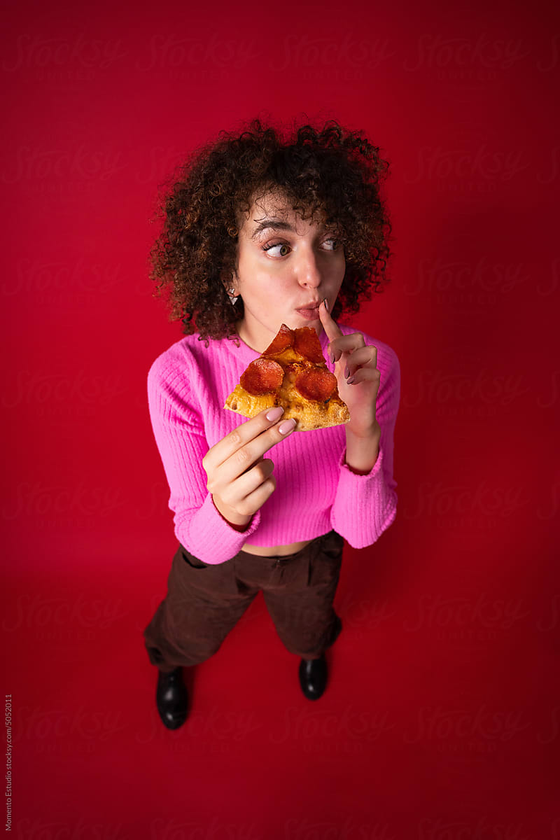 Delighted woman eating slice of pizza