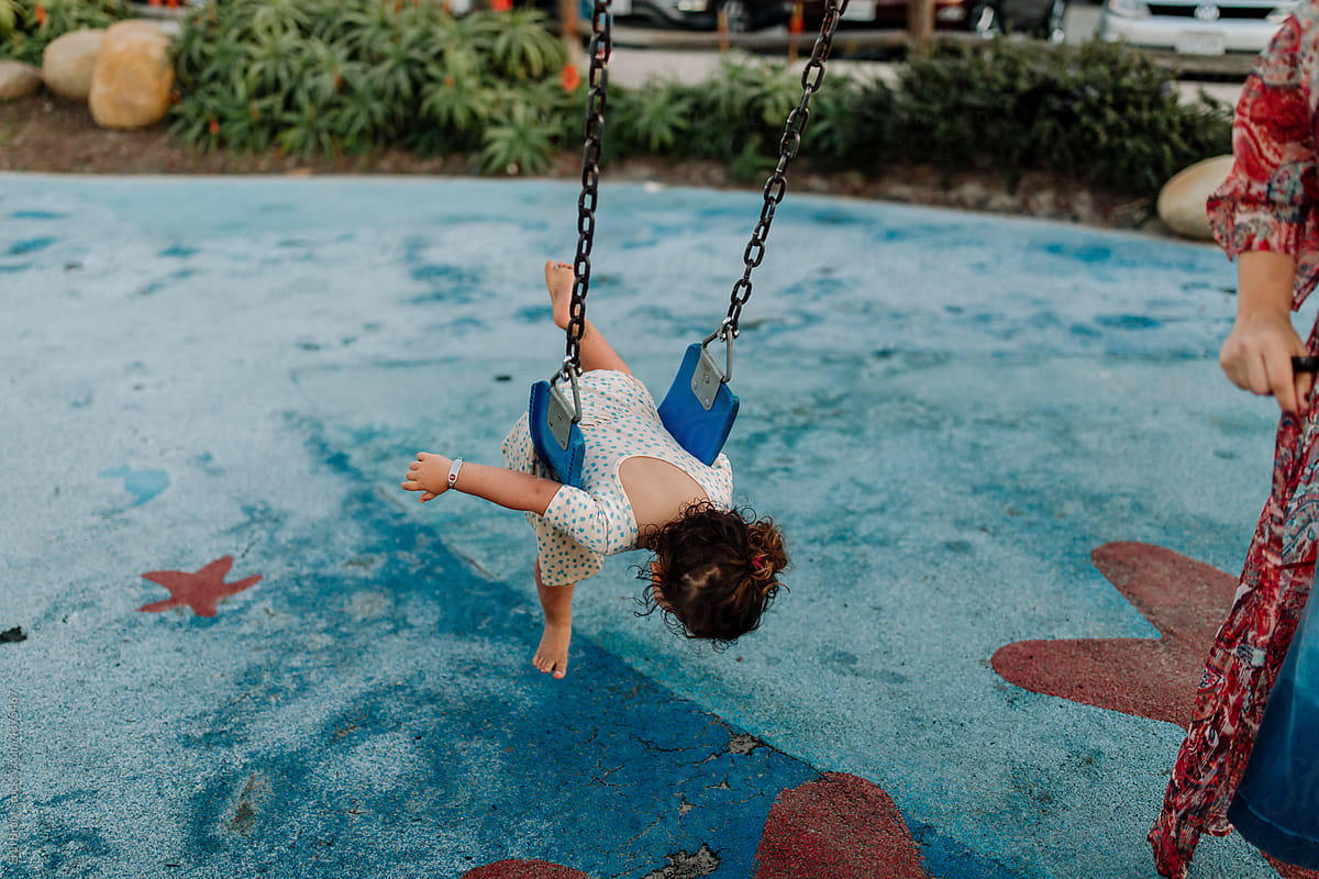 Young girl swinging face down at playground