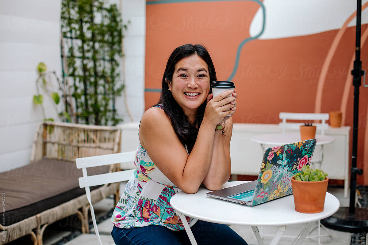 Smiling Asian woman with coffee outside