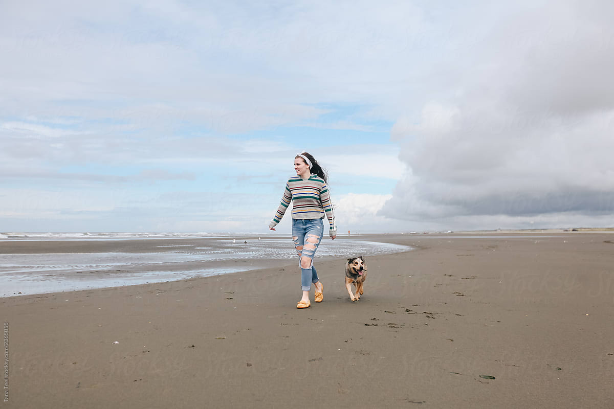 young woman plays with dog on the beach