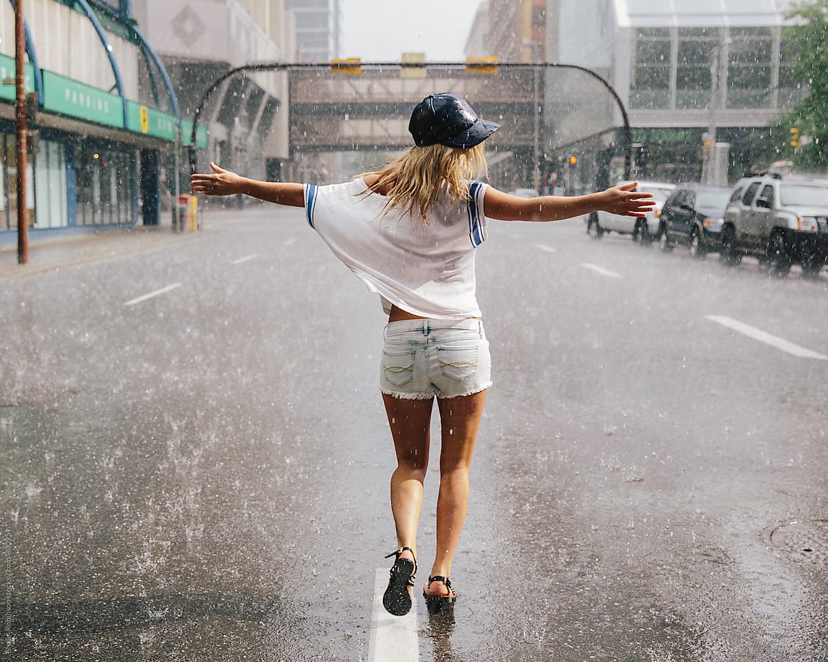 Young woman dancing in the rain on an empty street