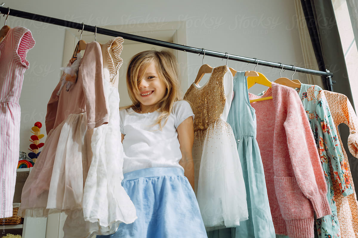 Girl choosing dresses standing by a clothing rack