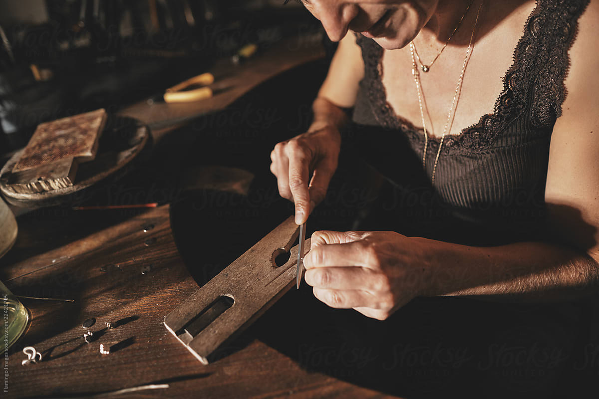 Female jeweler filing a ring at her studio workbench