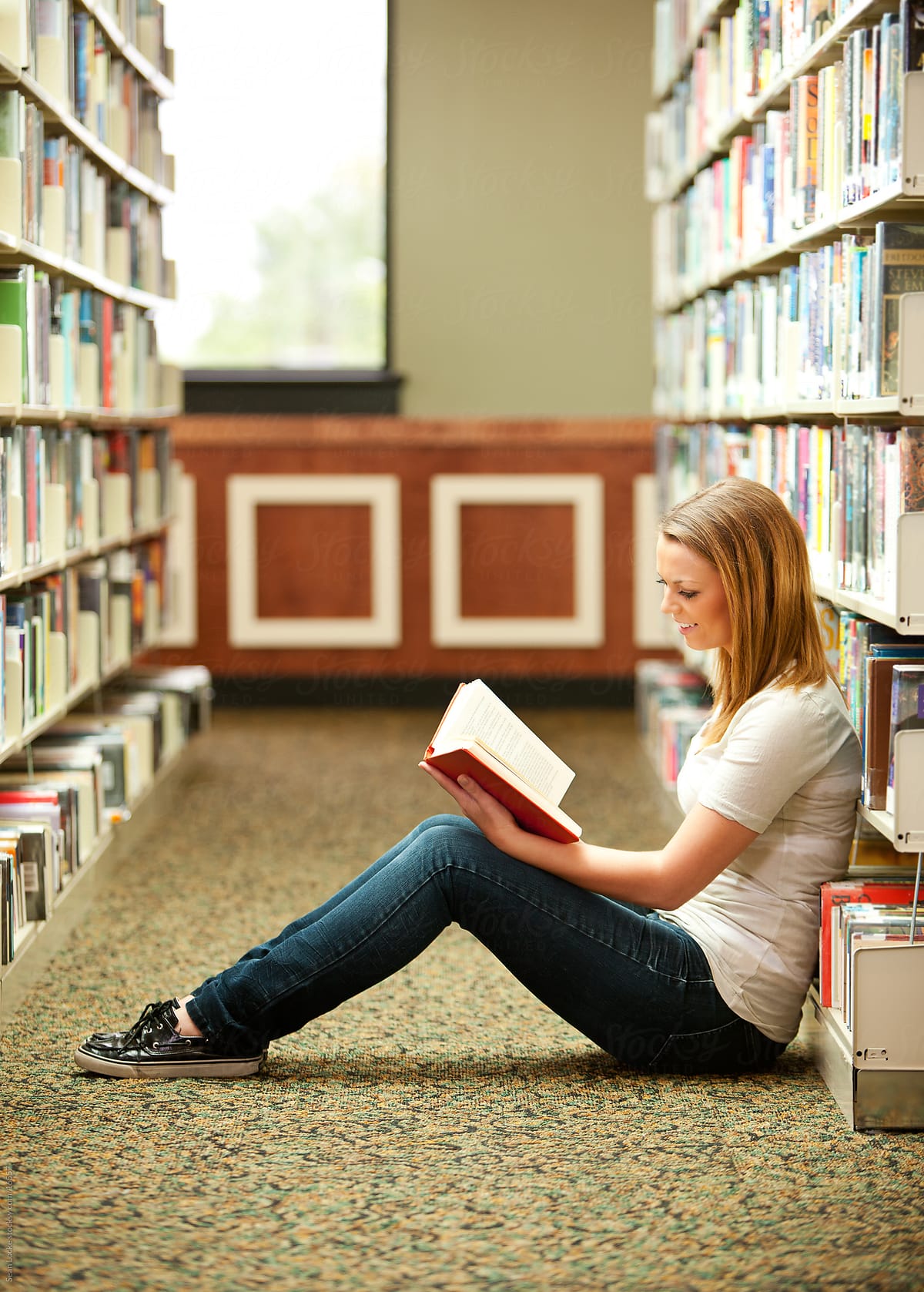 Library: Girl Sitting on Floor, Reading a Book