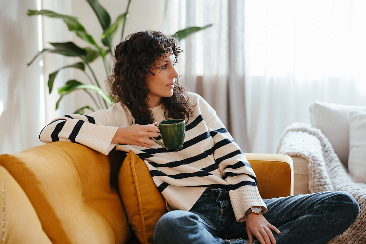 Woman drinking hot beverage on sofa