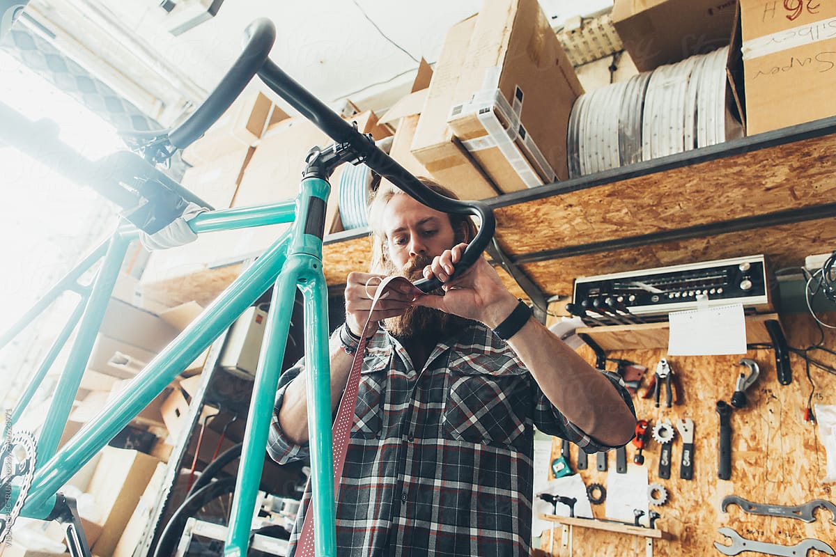 Bicycle Mechanic Putting Pink Grip Tape on Handlebar of Race Bike
