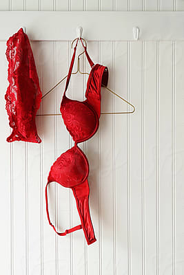 Closeup Of Red Lace Bras And Panties Hanging On Hooks by Stocksy