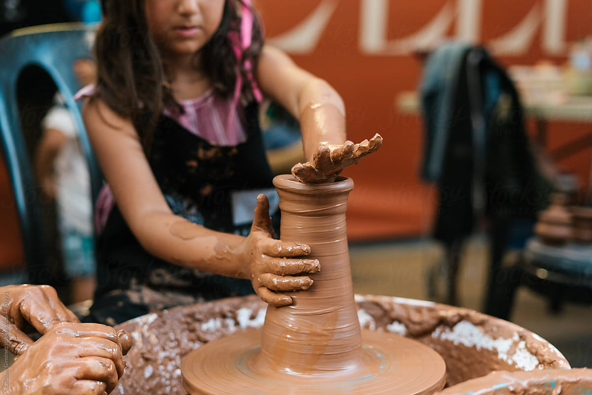 Anonymous girl shaping clay vase in workshop