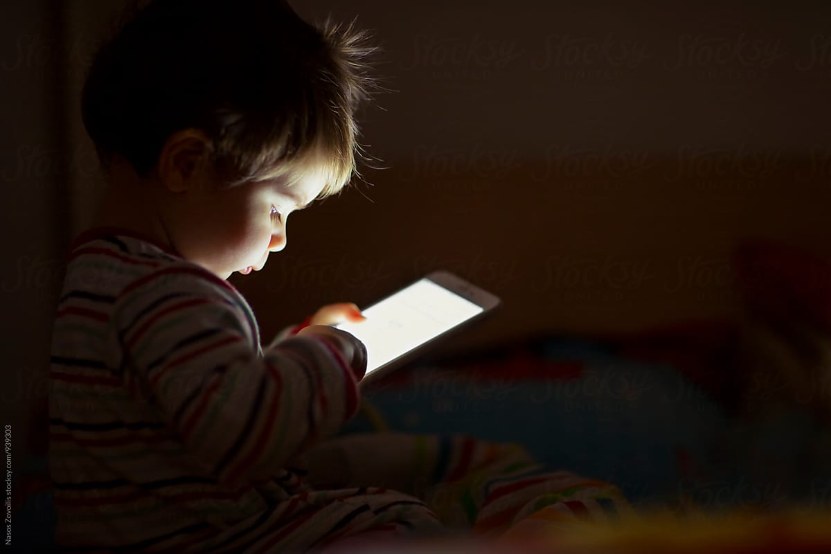 1 year old boy looking a digital tablet in the dark