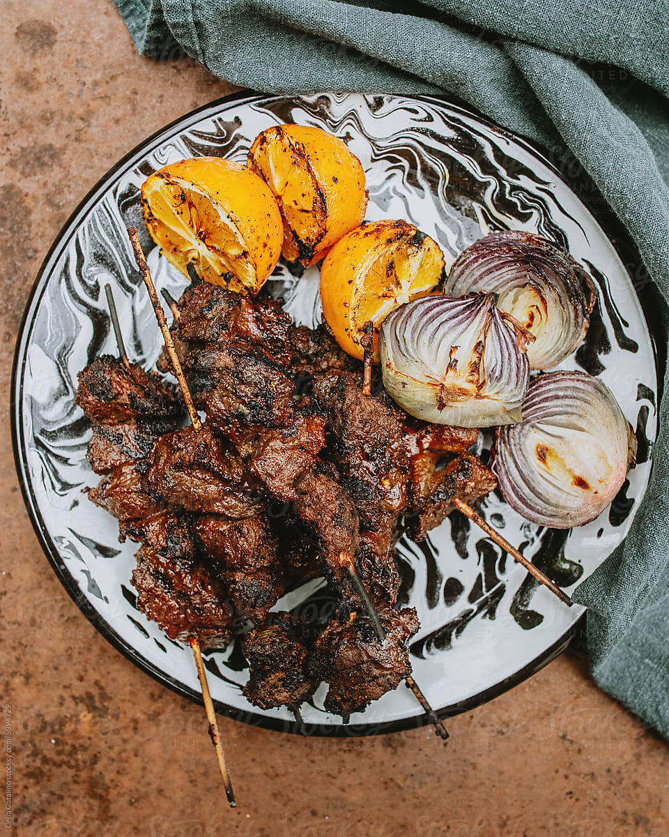 Beef Kebabs Served with Grilled Onions and Lemons