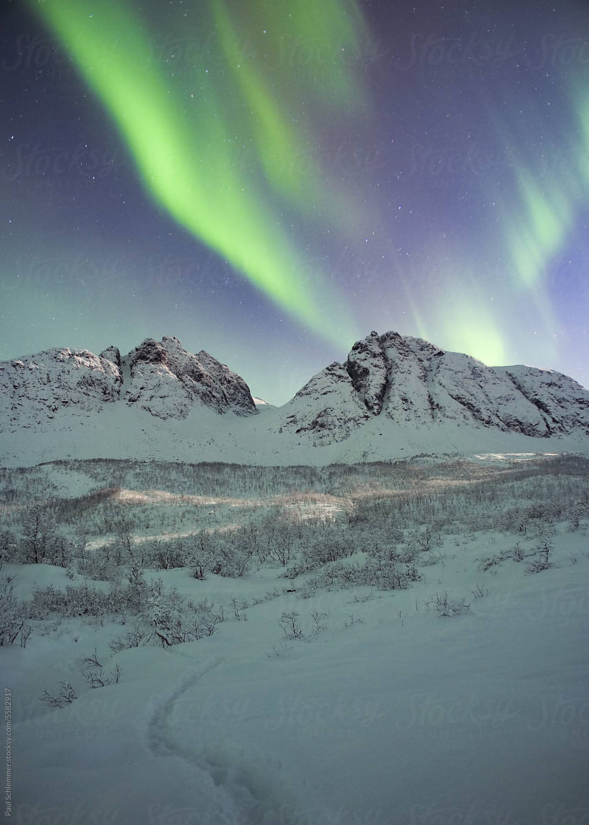 Snow covered mountain range under northern lights