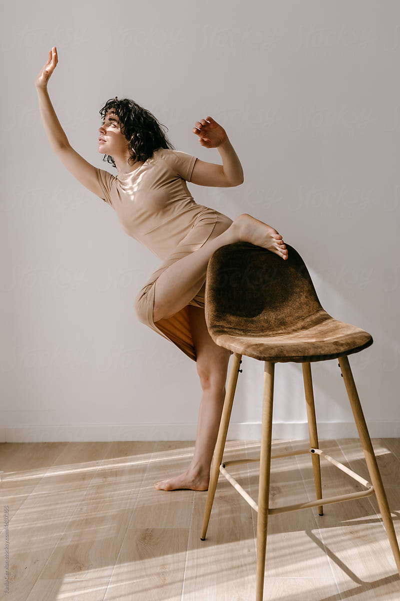 Barefooted lady with leg on chair and raised arms