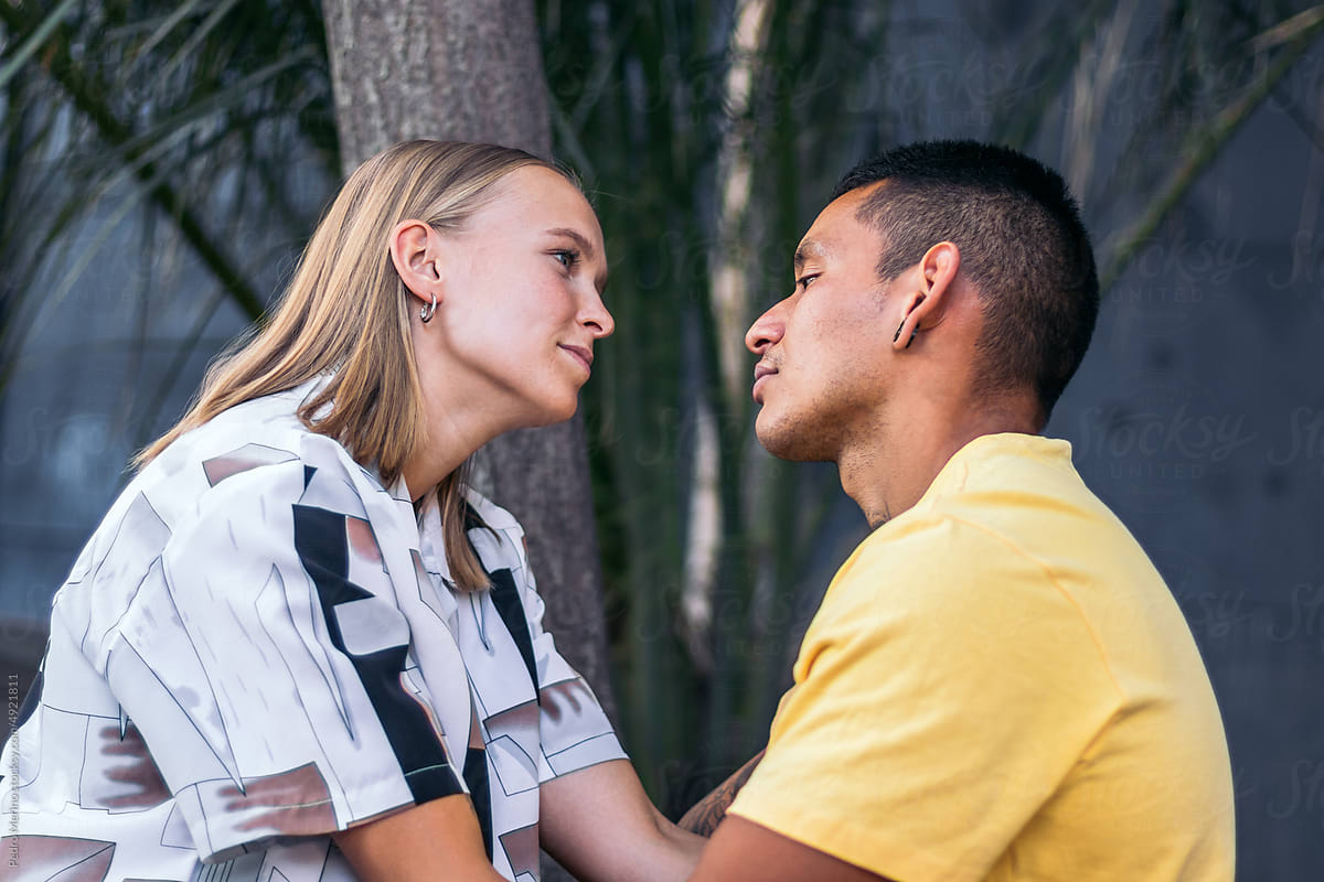 Multi-ethnic couple looking into each other\'s eyes outdoors