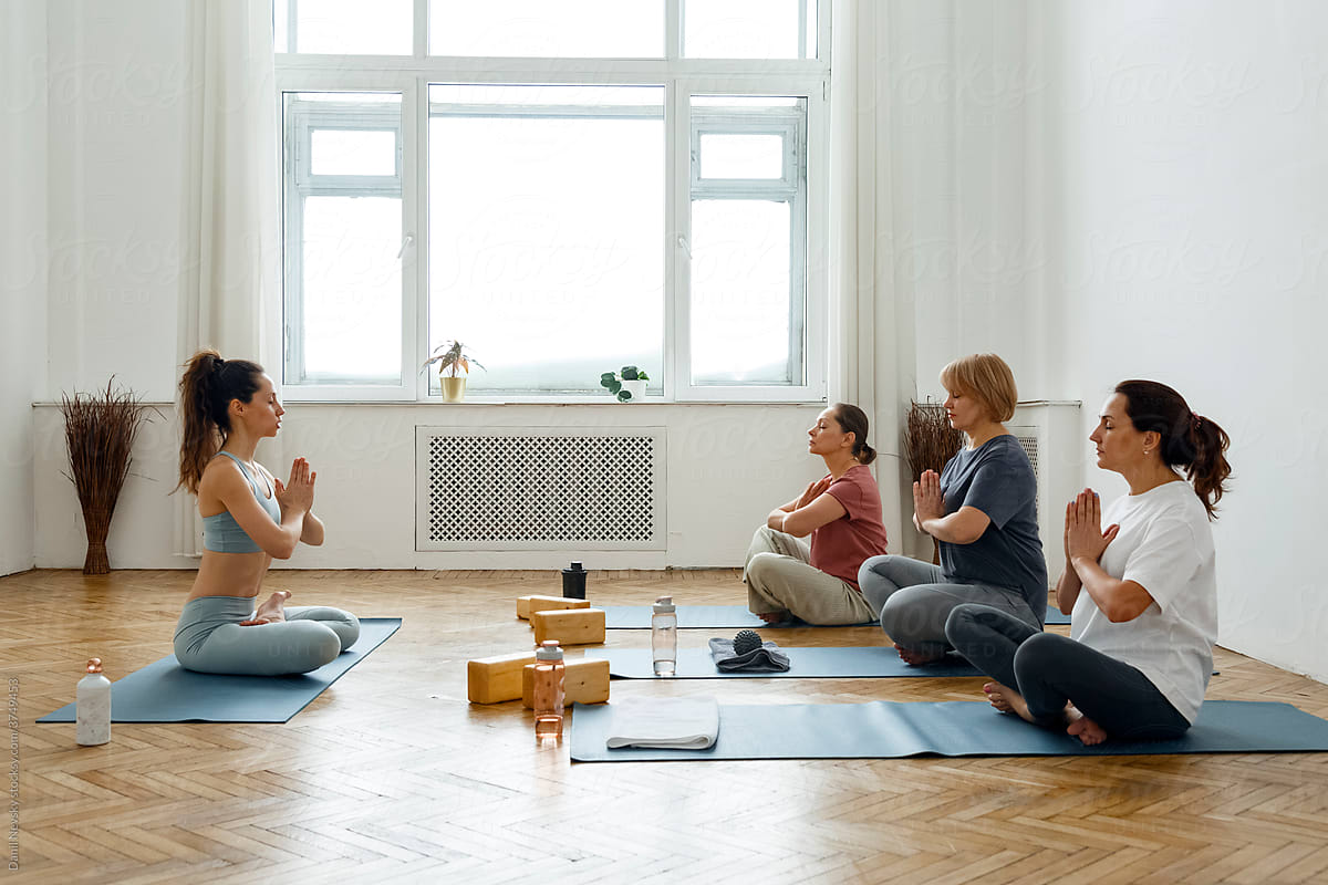 Company of women practicing yoga with instructor in studio